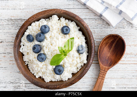 Cottage cheese, ricotta or tvorog with blueberries in wooden bowl on old white wooden table. Top view Stock Photo