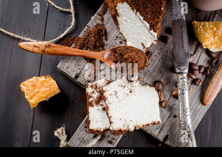 soft homemade cheese wrapped in ground coffee and a cup of coffee with milk breakfast on a wooden table Stock Photo