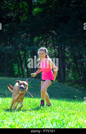 Little girl plays with her German shepherd dog in the meadow. Stock Photo