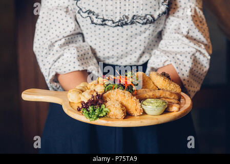 woman holding a plate of snacks for beer with different sauces on parchment Stock Photo