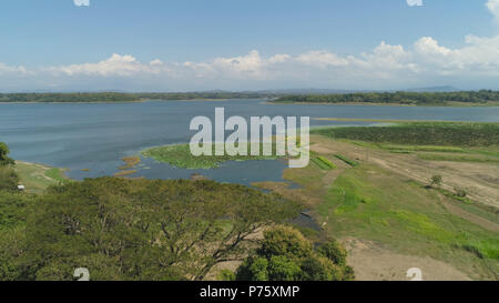 Aerial view of Paoay Lake with water lilies, Philippines. Lake against background of mountains and sky with clouds. Paoay Lake National Park, Ilocos Norte. Stock Photo