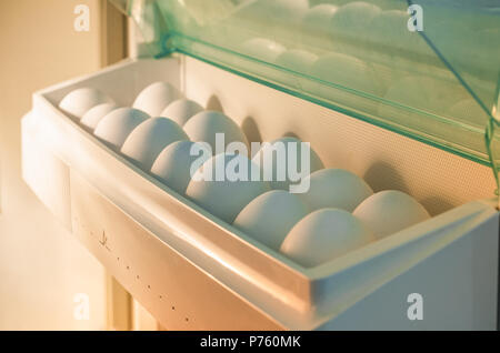 Dozen on white eggs in the fridge compartment Stock Photo