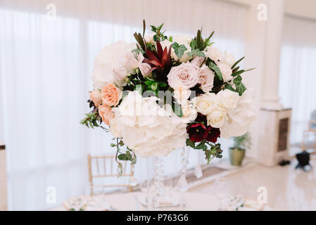 Magnificent, volume bouquets of flowers in high glass vases. Wedding flowers on tables for guests Stock Photo