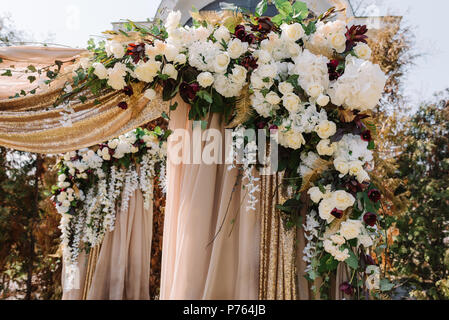 Magnificent wedding arch for a wedding ceremony. The square arch decorated by golden fabric and flowers Stock Photo