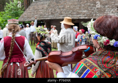 People in Latvian national costumes are dancing on the street in the countryside in summer Stock Photo
