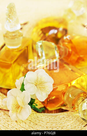 Several vintage bottles of perfume with the glass stoppers and  artificial flowers of jasmine as a nice background Stock Photo