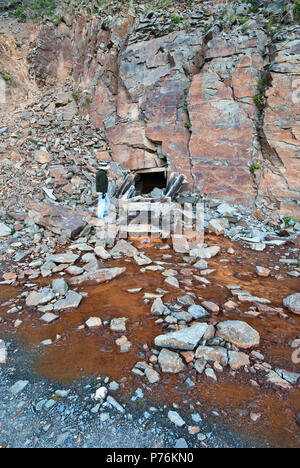 Man at adit, entrance to old mine, rust colored water coming out of tunnel, road to Clear Lake, San Juan Mountains, near Silverton, Colorado, USA Stock Photo