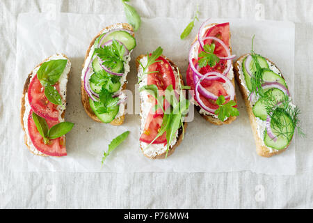 Bruschetta or sandwiches with tomatoes, cucumbers and cream cheese, decorated with greens. Stock Photo