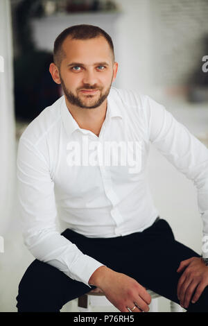Handsome and confident man with bread posing on chair. Stock Photo