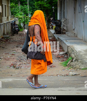 Bodhgaya, India - July 9, 2015. A monk walking on rural road in Bodhgaya, India. Bodh Gaya is the most revered of all Buddhist sacred sites. Stock Photo