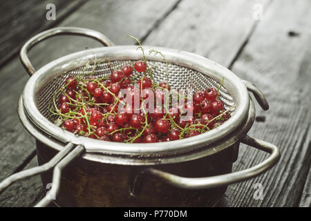 Red currant in a colander on a black wooden table Stock Photo