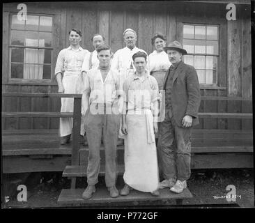 . Cooks at Linco Log and Lumber Company. English: Six cooks for the Linco Log and Lumber Company stand in front of the wood frame mess hall. A woman is in the back row and two teenage boys stand in the front row. Another man who could be the boss stands to the right. 3 March 1920 3 Cooks at Linco Log and Lumber Company Stock Photo