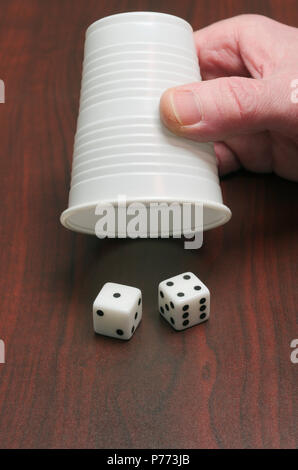 two dice and a hand holding a dice cup Stock Photo