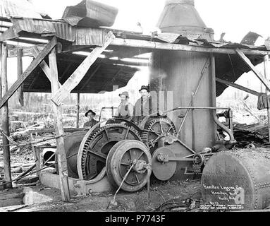 . English: Logging crew and donkey engine, Hamilton Logging Company, ca. 1912 . English: Caption on image: Hamilton Logging Co., Hamilton, Wash. Kinsey Photo. No. 13 PH Coll 516.1439 The English Lumber Company had a controlling interest in the Hamilton Logging Company, which did business under that name from ca. 1908 to 1917, when the name was changed to the Lyman Timber Company. Hamilton is a community on the north bank of the Skagit River ten miles east of Sedro Woolley in central Skagit County. It was once boomed as The Pittsburgh of the West because of iron and coal deposits in the vicinit Stock Photo