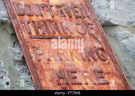 “Don’t even think of parking here”. Humorous No Parking message on a rusty textured old metal sign. Isle of Portland, Dorset, England, United Kingdom. Stock Photo