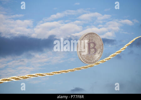 Bitcoin balancing on golden rope in the sky. Stock Photo