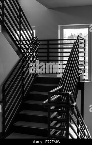 Stair well with metal railing and steps leading up to top floor Stock Photo