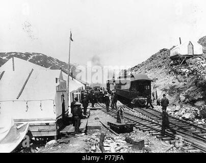 . English: Senator Charles Warren Fairbanks and party arriving on the White Pass and Yukon Railroad, summit of White Pass, Alaska, ca. 1899. English: Senator from Indiana and later Vice President under Theodore Roosevelt . Caption on image: 'Senator Fairbanks and party arriving at summit White Pass' Original image in Hegg Album 3, page 27. Subjects (LCTGM): Railroad locomotives--Alaska--White Pass; Railroad tracks--Alaska--White Pass; Tents--Alaska--White Pass; Legislators--United States Subjects (LCSH): White Pass (B.C.); Mountain passes--Alaska; Fairbanks, Charles W. (Charles Warren), 1852-1 Stock Photo