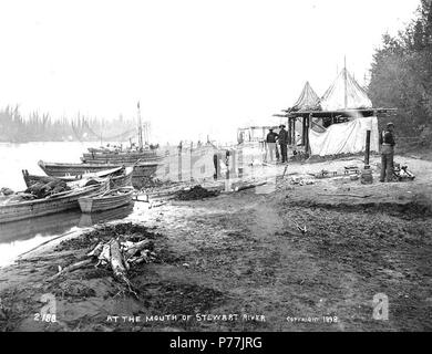 . English: Stewart City on the Stewart River, Yukon Territory, 1898. English: This settlement served as a wood point for steamboats and a stopping point for those headed toward the Klondike. Shows men with their boats tied up to the riverbank . Caption on image: 'At the mouth of Stewart River. c. 1898' Subjects (LCTGM): Rivers--Yukon; Rowboats--Yukon--Stewart City; Scows--Yukon--Stewart City; Tents--Yukon--Stewart City Subjects (LCSH): Stewart River (Yukon)  . 1898 12 Stewart City on the Stewart River, Yukon Territory, 1898 (HEGG 38) Stock Photo