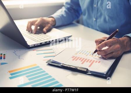 businessman analyzing annual business report with using laptop at office desk Stock Photo