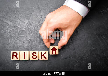 The realtor's hand stretches a cube with a house pattern to the word risk. The concept of risk, loss of real estate. Property insurance. Loans secured Stock Photo