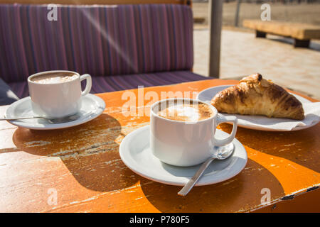 Two cups of invigorating cappuccino and a croissant Stock Photo