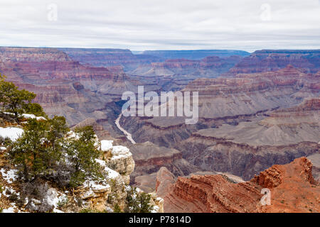 Winter view of the Grand Canyon from the South Rim looking west. Snow adorns the rocky outcrop of the nearby cliff; the Colorado River is below. Stock Photo