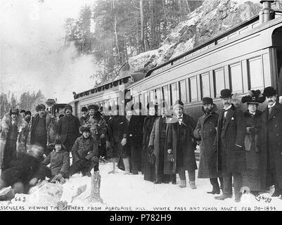 . English: Passengers disembarking from the White Pass & Yukon Railroad to view scenery from Porcupine Hill, Alaska, February 20, 1899. English: Caption on image: 'Passengers viewing scenery from Porcupine Hill. White Pass and Yukon Route. Feb 20 1899.' Original image in Hegg Album 2, page 36. Subjects (LCTGM): Railroads--Alaska--Porcupine Hill; Mountains--Alaska; Passengers--Alaska Subjects (LCSH): White Pass & Yukon Route (Firm); Porcupine Hill (Alaska); Portraits, Group--Alaska--Porcupine Hill  . 1899 10 Passengers disembarking from the White Pass &amp; Yukon Railroad to view scenery from P Stock Photo