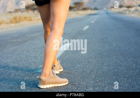 Female runner on the desert road low angle view Stock Photo