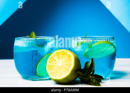 Blue cocktails decorated with lemon on matching background Stock Photo