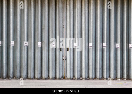 Sliding and folding industrial doors with No Smoking signs, a loading bay for delivery truck on a street of London city Stock Photo