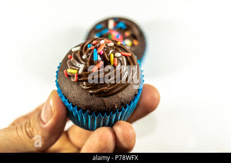 Personal perspective of a person holding a chocolate cupcake isolated on white background Stock Photo
