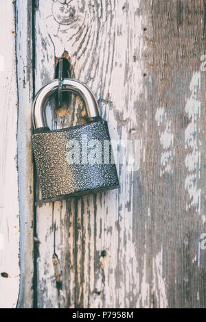 A small lock on an old wooden door with shabby paint Stock Photo