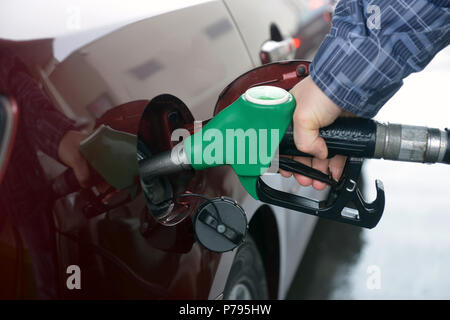 man hand refilling up gas tank of the car with green eco fuel on a filling station Stock Photo