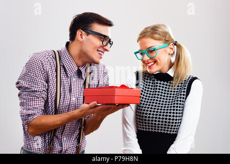 Nerdy man giving present to his nerdy girlfriend. Stock Photo