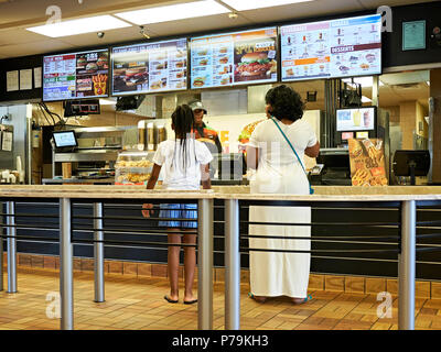 Woman and young girl being served inside in line at a Burger King fast food restaurant in Montgomery Alabama, USA. Stock Photo