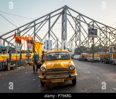 May 27,2018. Kolkata, india. A yellow Taxi parked on the Howrah Railway station overlooking the Howrah Bridge behind. Stock Photo