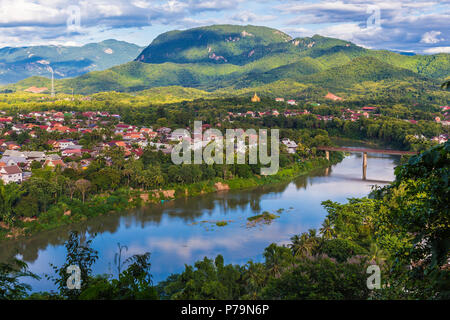 View of Luang Prabang and Nam Khan river in Laos with beautiful sunset light bathing the background mountains Stock Photo