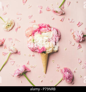 Flat-lay of waffle sweet cone with pink and white buttercup flowers over pastel light pink background, top view, square crop. Spring or summer mood co Stock Photo