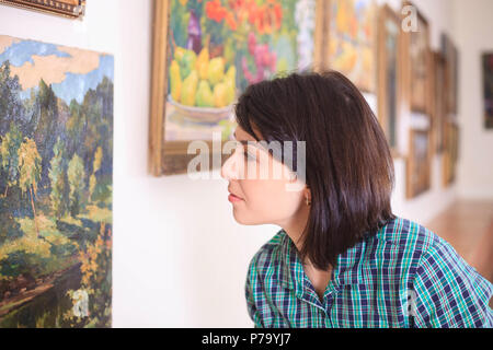 Young woman looking at painting in art gallery. Stock Photo