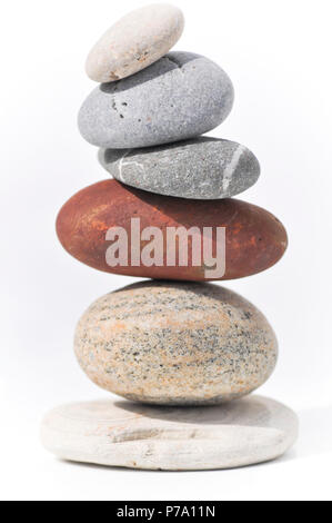 Six stones balancing on each other to create a tower of stones. Image is set against a white background Stock Photo