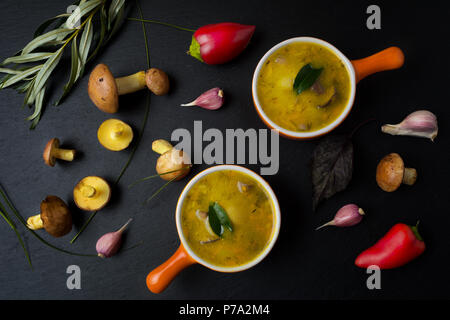 Mushroom cream sauce in the orange cocotte on the black background, top view. Vegetarian healthy food Stock Photo