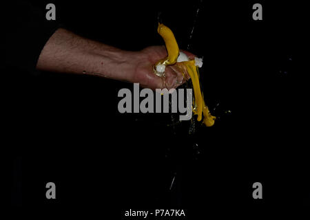 Cracking the eggs in the studio on a black background to show the details of the explossion and the yolk and egg white. Stock Photo