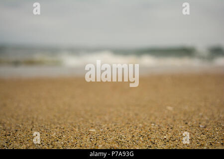 Closeup on a coarse sand beach in southern California on a pleasant overcast day with wave crashing in the background Stock Photo