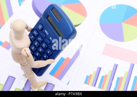 Wooden dummy with calculator on color chart printed documents background Stock Photo