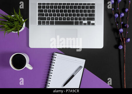 Laptop and notebooks on purple and black background. Work planning concept. Stock Photo