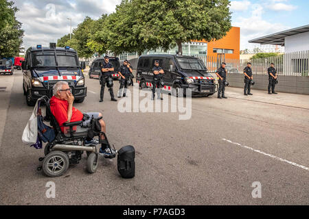 Barcelona, Catalonia, Spain. 5th July, 2018. A man in a wheelchair protests against the auction in front of the police.The popular mobilization against the public auction of a set of properties corresponding to intestate inheritances has managed to delay the start of the auction scheduled for 10:00 a.m. In spite of the strong popular resistance, the auctioneers and buyers have been accessing the site with the help of the Catalan police Mossos d'Esquadra. Throughout the morning there have been small confrontations between activists and police. (Credit Image: © Paco Freire/SOPA Images via ZUMA Stock Photo