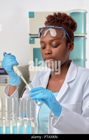 African-american scientist or graduate student in lab coat and protective wear works in modernl laboratory Stock Photo
