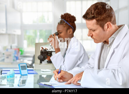 Scientists, male and female, working in research facility Stock Photo