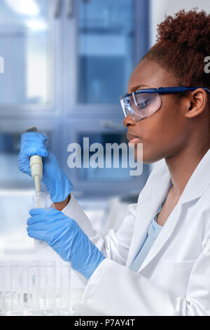 African-american scientist or graduate student in lab coat and protective wear works with automatic pipette in modernl laboratory Stock Photo